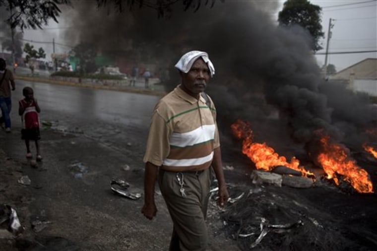 A man walks past a barricade of burning tires and rocks blocking a street in Port-au-Prince, Haiti, Thursday Dec. 9, 2010.  The barricade was set up by supporters of eliminated presidential candidates to protest the announcement that only government protege Jude Celestin and former first lady Mirlande Manigat would advance to a presidential runoff election. Haiti's electoral council says it will recount the ballots in the country's disputed presidential election.  (AP Photo/Ramon Espinosa)